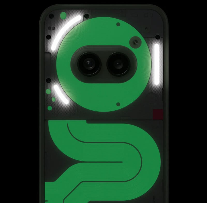 Close-up of a phone's back panel, featuring glowing green and white circuit patterns and dual camera lenses. The design is futuristic and tech-oriented, displaying various geometric shapes and lines. The lighting highlights the intricate detailing.