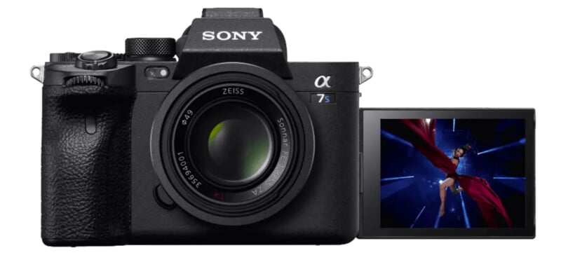 A Sony Alpha camera with a ZEISS lens is shown. Its flip-out screen displays a vibrant image of a person wearing a flowing red outfit against a dark blue background. The camera's brand and lens details are clearly visible.