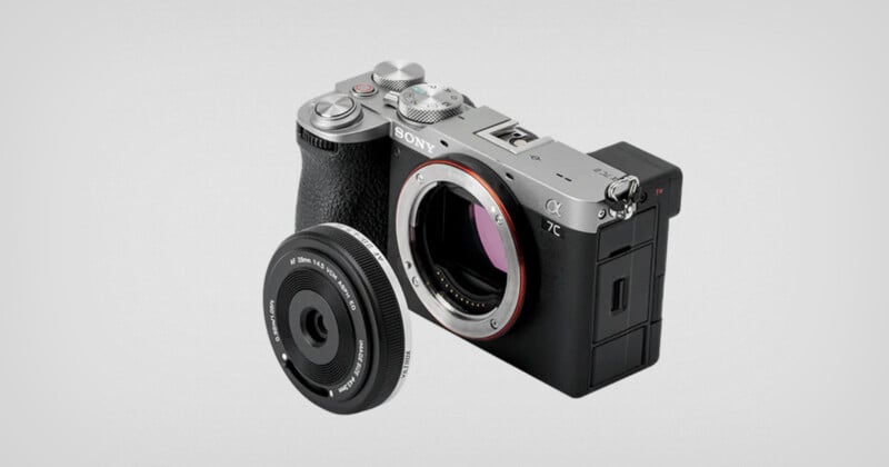 A silver and black Sony camera body without a lens is displayed on a light grey background. To the left of the camera, there is a detached lens with visible connectors facing the viewer.