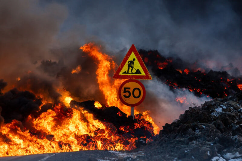 A road construction warning sign with a speed limit of 50 stands amidst a backdrop of intense flames and thick smoke, creating a dramatic and hazardous scene.