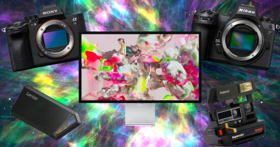 A colorful, abstract background features two digital cameras, a Sony on the left and a Nikon on the right. In the center is a monitor displaying abstract art. Below are a Lexar memory drive and a Polaroid camera with a flash attachment.