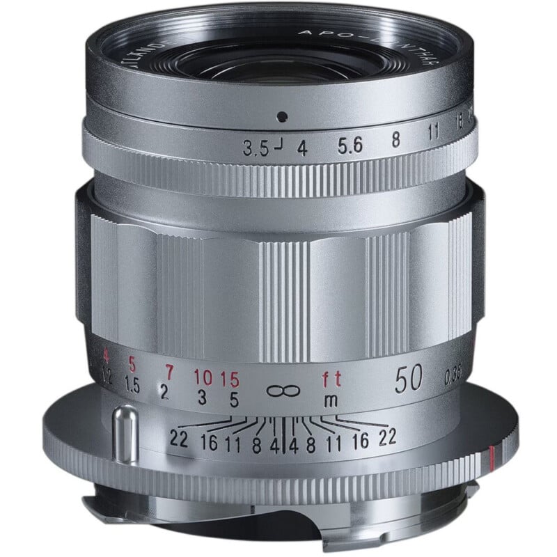 A silver camera lens with aperture and focus rings, featuring engraved numbers and markings. The lens is set to an aperture of f/5.6 and a 50mm focal length. The design is sleek and metallic, with a classic, polished look.