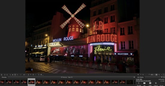 A night view of the Moulin Rouge in Paris, featuring its iconic red windmill and bright neon lights. The building is illuminated against the dark sky, with pedestrians and cars visible in the foreground.