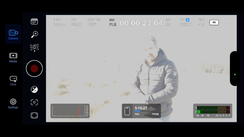 A person in a puffy jacket stands outside in a bright, overexposed environment. Camera interface details, including recording time and settings, are visible on the screen overlay.