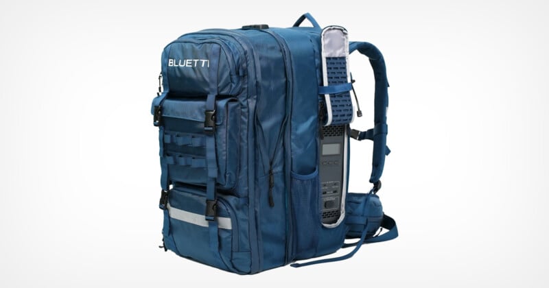 Blue backpack with multiple compartments and straps. Features a built-in power station on one side, displaying a screen and several charging ports. The brand "Bluetti" is visible on the top flap.