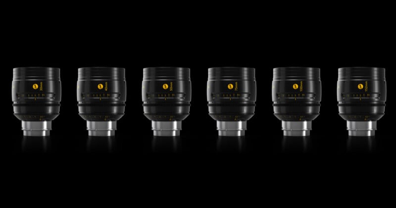 A row of six identical black camera lenses on a reflective black surface, evenly spaced against a black background. Each lens features yellow markings and a silver base, highlighting their sleek, modern design.