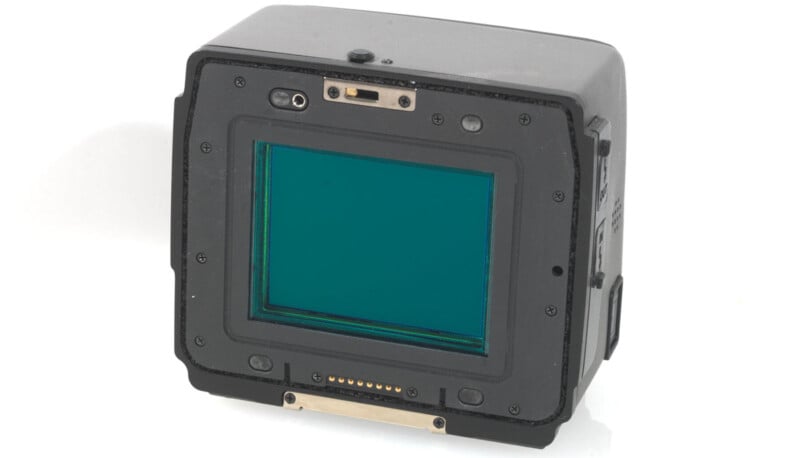 A close-up image of a digital camera sensor with a rectangular shape and a blue-green tint. The sensor is encased in a black housing with various buttons and connectors visible.