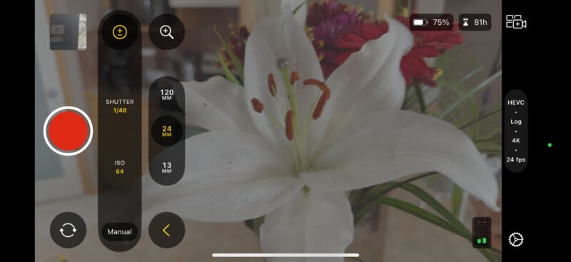 A close-up of a white lily with prominent stamens, set against a bouquet of red and purple flowers. A camera interface is displayed over the image, showing settings like ISO, shutter speed, and battery life.