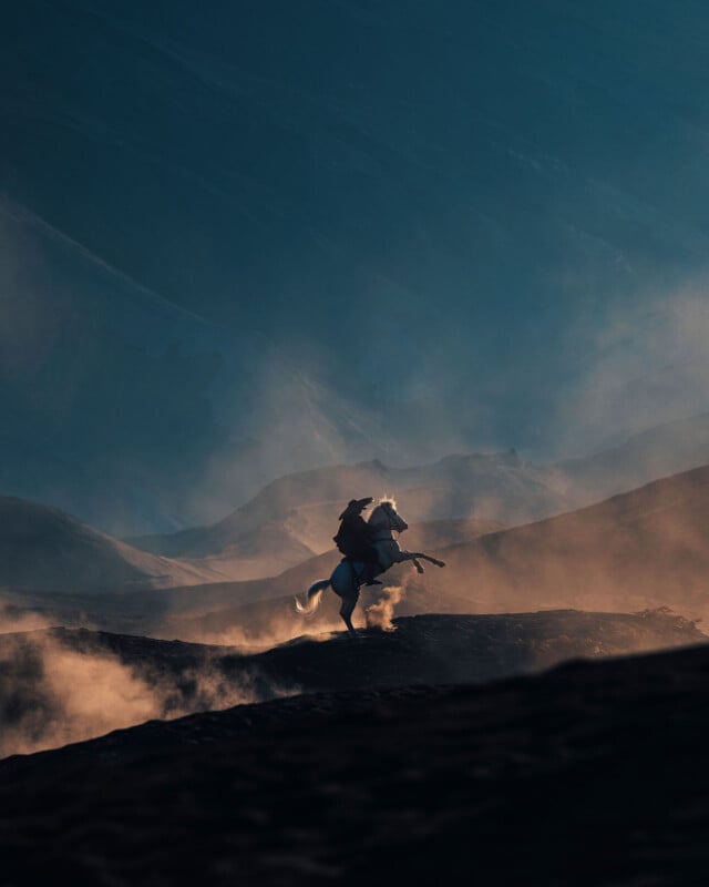 Silhouette of a horse and rider rearing on a dusty hillside at sunset. The background features a dramatic, misty landscape with soft, diffused lighting highlighting the rugged terrain.