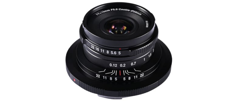 A black camera lens with various markings, including focal length and aperture settings. The lens has a compact design and prominent focus and aperture rings, with numbers indicating settings for photography adjustments.