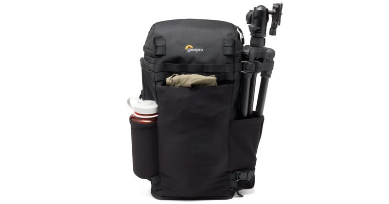 A black camera backpack with the Lowepro logo, featuring compartments holding a water bottle, a folded jacket, and a tripod on the side. The design is sleek and functional, suitable for photography gear.