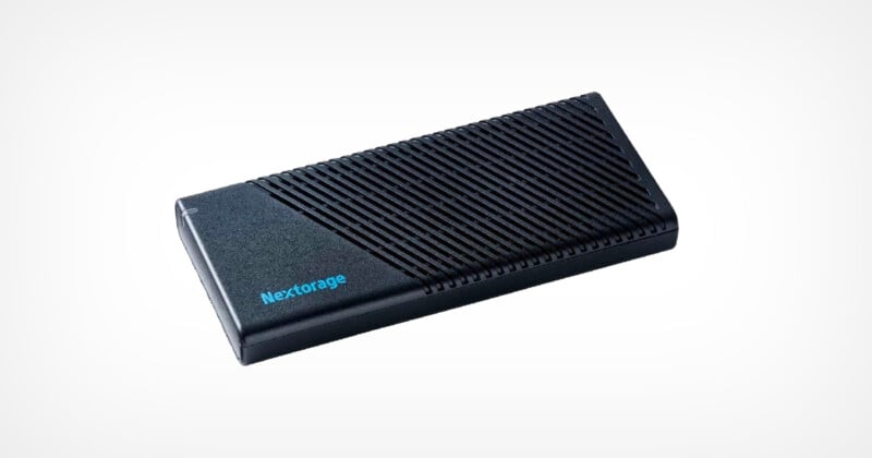 A black Nextorage external SSD with a sleek, compact design. The top surface features diagonal grooves, and the brand name is printed in blue. The SSD is positioned against a plain white background.