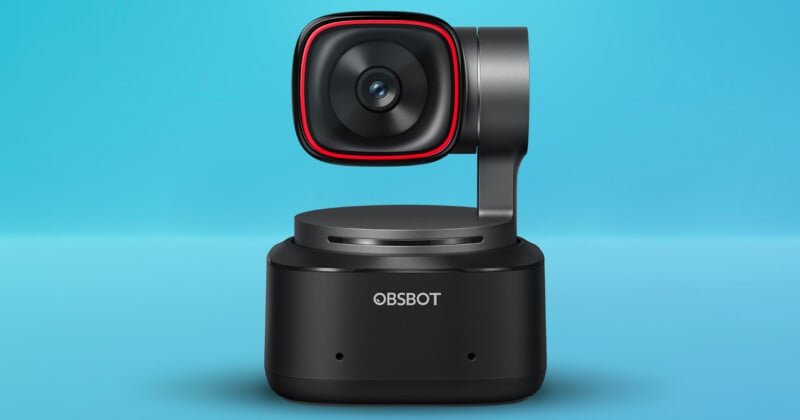 A compact OBSBOT webcam with a sleek black design and red accents on a light blue background. Designed for enhanced video capturing, featuring a rotatable camera on a sturdy base.