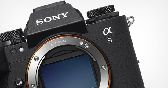 Close-up of a Sony Alpha a9 camera body, featuring the E-mount without a lens attached. The camera's branding is visible on the top, and its texture and control dials are highlighted against a white background.