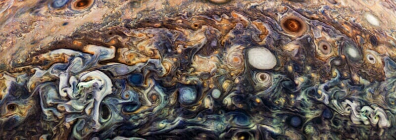 A swirling, colorful close-up of Jupiter's atmosphere, showcasing its turbulent clouds in hues of brown, orange, blue, and white, with various circular patterns and storms resembling artistic brushstrokes.