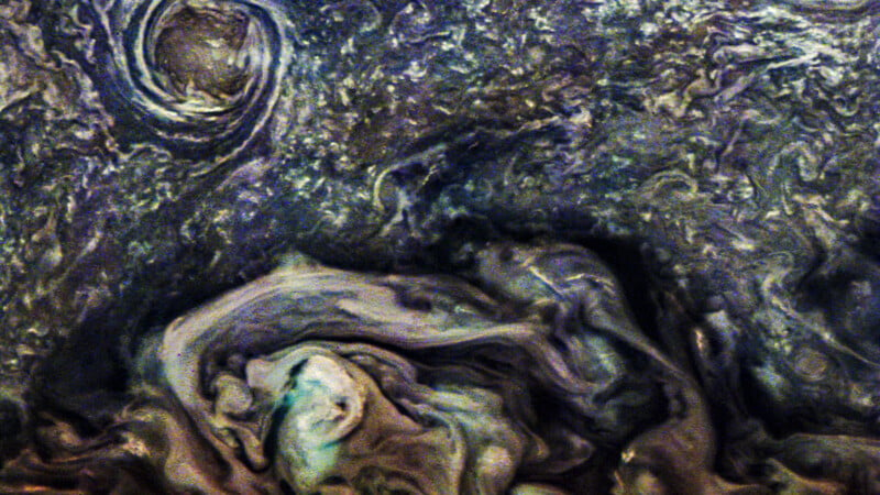 A swirling, abstract pattern of dark and light shades resembling a turbulent storm, with circular formations and wavy lines, reminiscent of a painting or outer space phenomena.