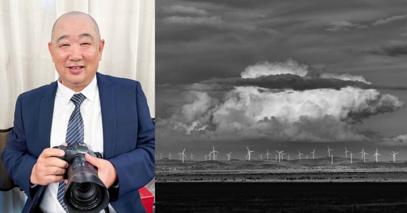 Un homme en costume tient un appareil photo à côté d’une image de paysage en noir et blanc d’éoliennes sous un ciel nuageux.