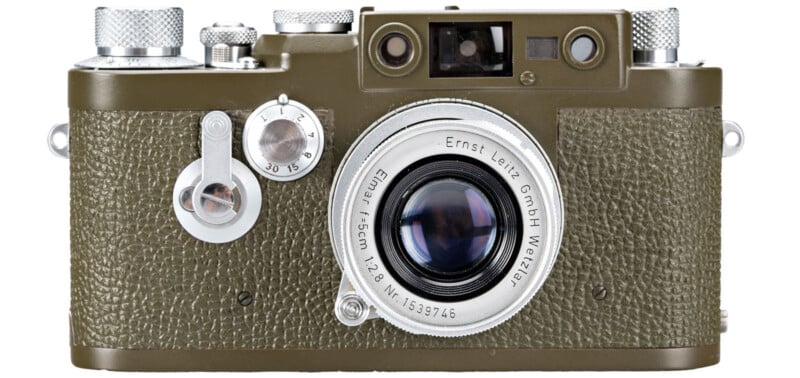 A vintage olive green Leica camera with a textured body is shown. It features a prominent lens labeled "Ernst Leitz GmbH Wetzlar," alongside various dials and knobs on the top and side.