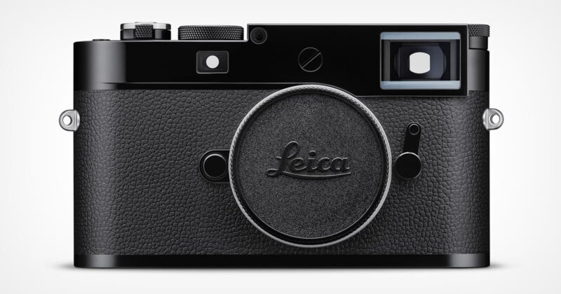 A black Leica camera with a textured grip is shown from the front. The lens cap features the Leica logo, and various buttons and dials are visible on the top. The viewfinder is on the top right.