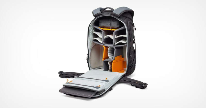 A gray and black backpack is open, showing its interior compartments. The inside is padded with multiple adjustable dividers in gray and orange tones, designed for organizing and protecting items, such as photography or electronic equipment.