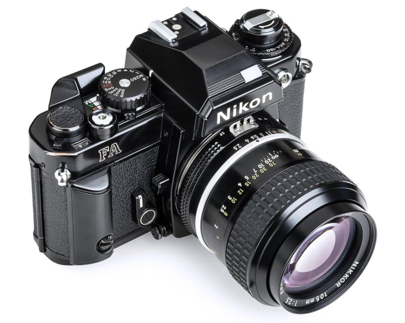 A Nikon FA film camera with a 50mm lens, featuring black body design, various dials, and a textured grip. The lens is marked with focal length details, and the camera appears in excellent condition against a white background.