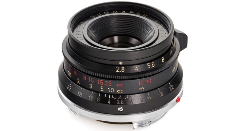 A close-up image of a vintage camera lens with focus and aperture rings, featuring measurements in feet and meters. The text "Summaron" is visible on the lens. The lens has a metal body with black and silver detailing.