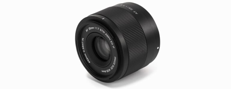 A black camera lens with a textured focus ring and branding details, including "AF 35mm f/1.7." The lens features a silver accent and is set against a plain white background.