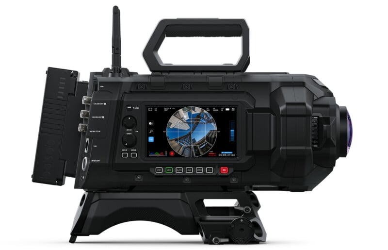 A black professional video camera with various buttons and dials. It features a large viewfinder displaying a colorful graphic interface. The camera has a handle on top and connectors on the side.