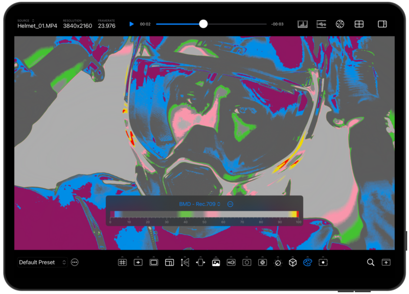 A digitally altered image of a person wearing a helmet and goggles. The image has been colorized with vibrant hues, including blue, pink, and green, creating a high-contrast, abstract appearance on a tablet screen displaying editing software controls.