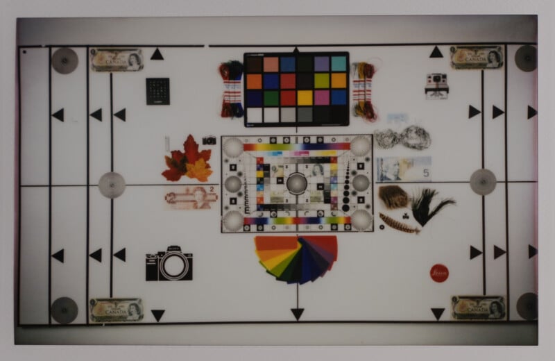 A variety of items arranged on a white background, including currency notes, a camera icon, colorful leaves, a color chart, measuring tools, and small objects. A rainbow fan is spread out near the center.