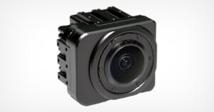 A square, compact black camera with a sleek design, featuring a circular lens in the center. It has a matte finish with subtle detailing, set against a plain white background.