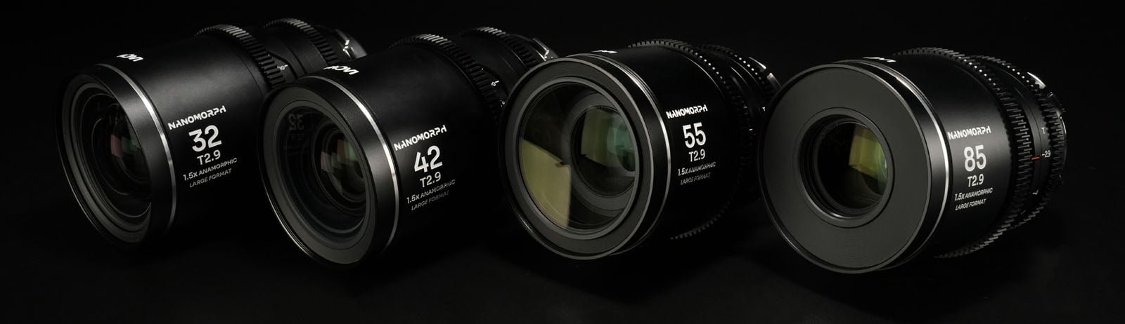 A row of four camera lenses of varying sizes on a black surface, each labeled with different focal lengths: 32mm, 42mm, 55mm, and 85mm, and marked with T2.9. The lenses are black with visible brand labels.