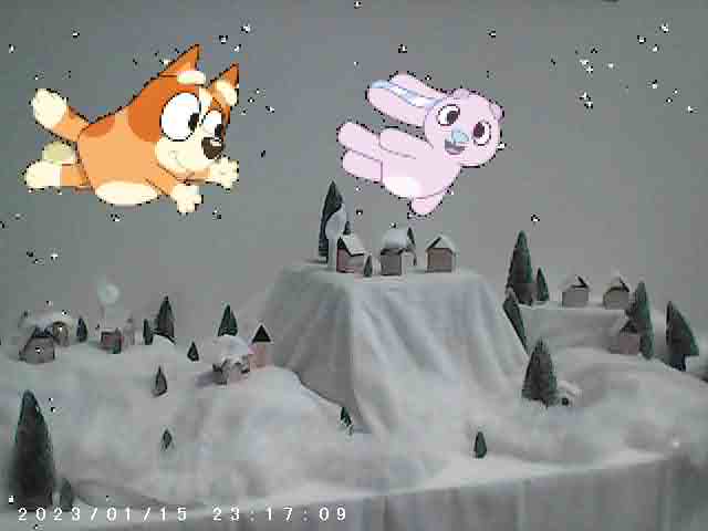 A snowy landscape with small houses and trees. Two animated characters, a dog and a rabbit, are flying in the sky above the scene. The image has a timestamp at the bottom.