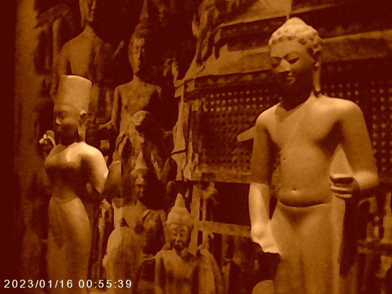 A sepia-toned image of a museum exhibit featuring several statues. Two prominent statues stand in the foreground, while others, including seated figures, are visible in the background. The display is dated 2023/01/16.