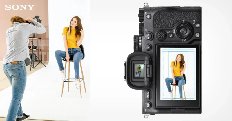 A photographer takes a picture of a woman in a yellow top and jeans sitting on a stool. The camera screen displays the photo being taken. Sony branding is visible on the backdrop.