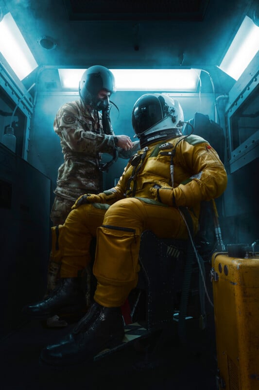 A person in a futuristic military uniform assists another person wearing a yellow spacesuit, seated inside a high-tech vehicle with neon lighting. The scene is enveloped in a smoky atmosphere.