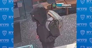 Person wearing a dark hoodie and backpack walking inside a building. Background features NYPD Crime Stoppers logos and contact information.