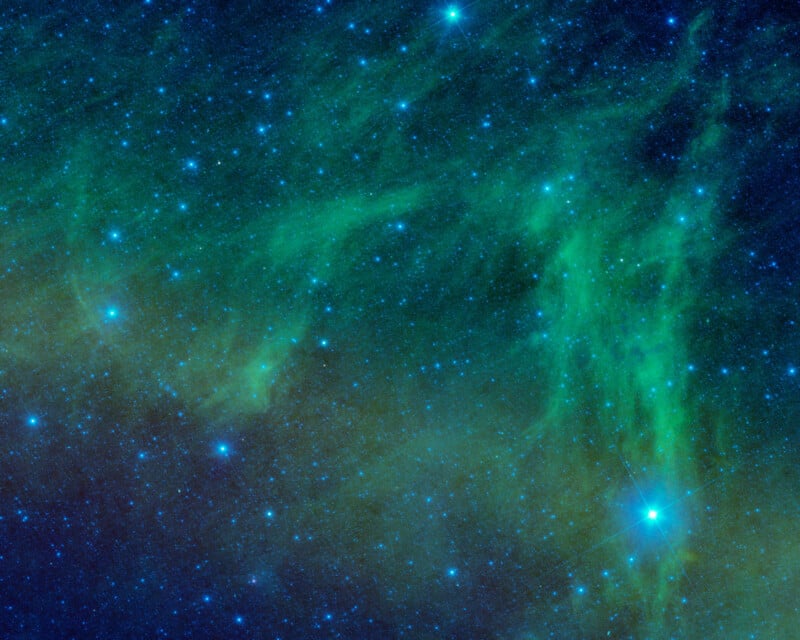 A vibrant image of outer space, displaying a dense cluster of bright stars scattered across a blue and green nebula. The colors blend to create a cosmic tapestry, with luminescent clouds and sparkling star points.