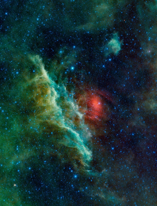 A colorful nebula in deep space with bright stars scattered across. Wisps of green, red, and blue gases create intricate patterns against a dark backdrop.