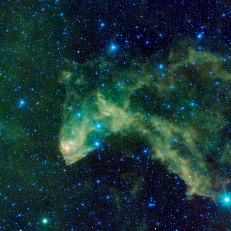 A cosmic scene with swirling green and yellow nebula resembling a horse's head against a backdrop of blue and white stars scattered across a dark space. The nebula appears to glow with a subtle ethereal light.