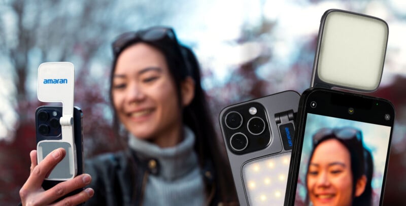 A smiling woman takes a selfie with a smartphone using an attached Amaran LED light. The phone's screen displays her image, with a focus on the lighting accessory. Background shows blurred trees and a cloudy sky.