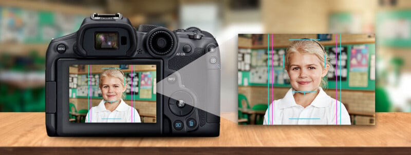 A digital camera on a wooden table displays the image of a smiling young girl with blonde hair on its screen. The background suggests a classroom setting, with blurry educational posters and a chalkboard visible.