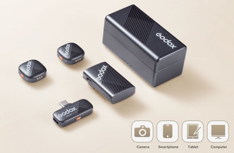 A set of Godox wireless microphone transmitters and receivers. They are displayed on a light background. Icons at the bottom show compatibility with camera, smartphone, tablet, and computer.