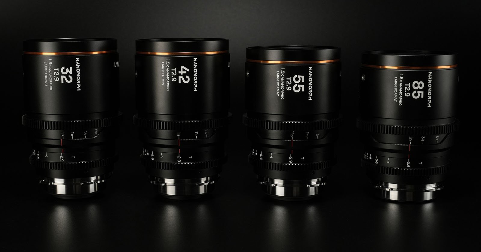 Four camera lenses are lined up against a dark background. Each is labeled with focal lengths: 32mm, 42mm, 55mm, and 85mm. The lenses have a sleek black design with orange accents on the top edges.