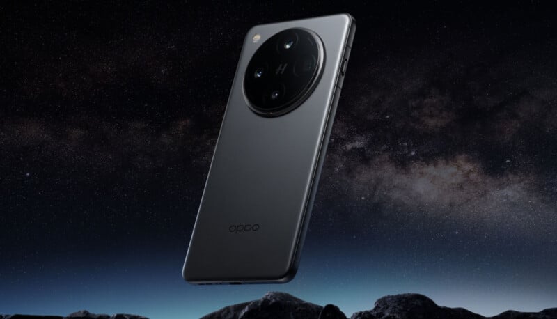 A sleek smartphone with a large circular camera module on the back hovers above a rocky landscape under a starry night sky. The phone's design is modern and minimalistic.