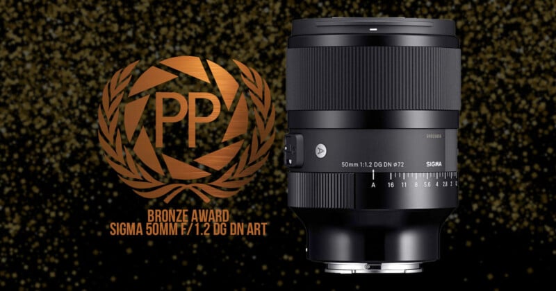 Image of a Sigma 50mm F1.2 DG DN Art lens against a glittery, dark background. Text reads "PP Bronze Award Sigma 50mm F1.2 DG DN Art" with a laurel wreath design around "PP.