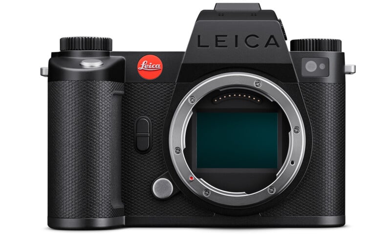 A black Leica mirrorless camera with a prominent red Leica logo on the front, featuring a textured grip, multiple control dials, and an exposed lens mount. The camera appears sleek and modern in design.