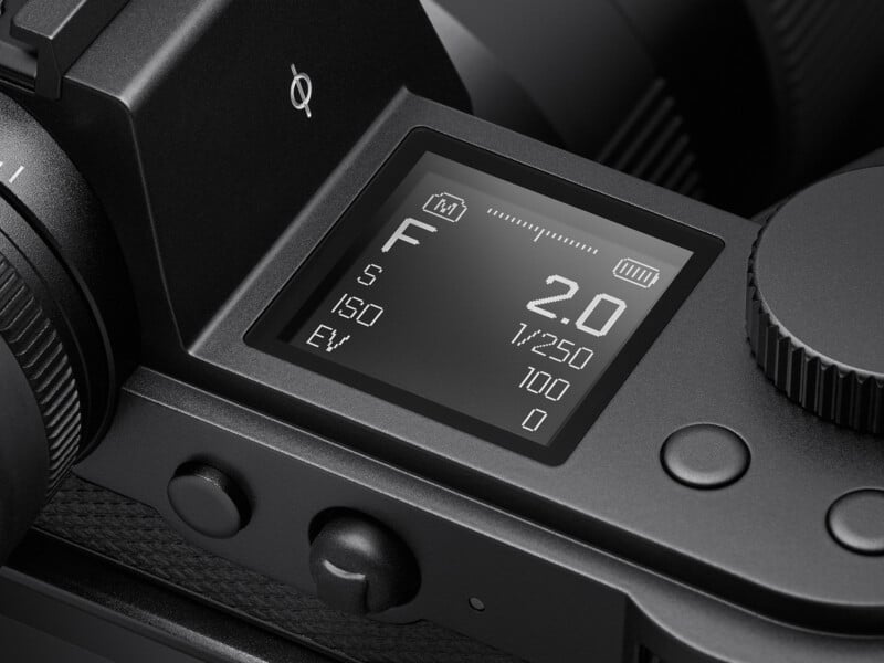 Close-up of a camera's digital display showing settings: focal length (F) at 2.0, shutter speed (1/250), ISO at 100, and exposure value (EV) at 0. Surrounding controls include dials and buttons for adjusting settings.