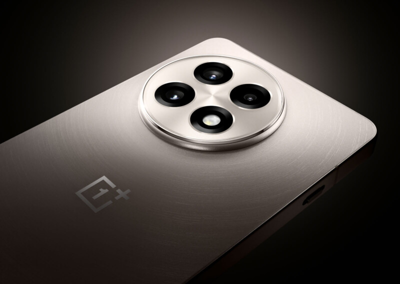 A sleek, metallic smartphone with an embossed logo and a circular quad-camera module is shown. The device is angled, highlighting its brushed finish and elegant design against a dark background.