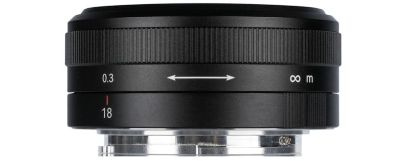 A black camera lens with markings indicating focus distances from 0.3 meters to infinity and focal length of 18mm. The lens has a sleek design with a metal mount on the bottom.